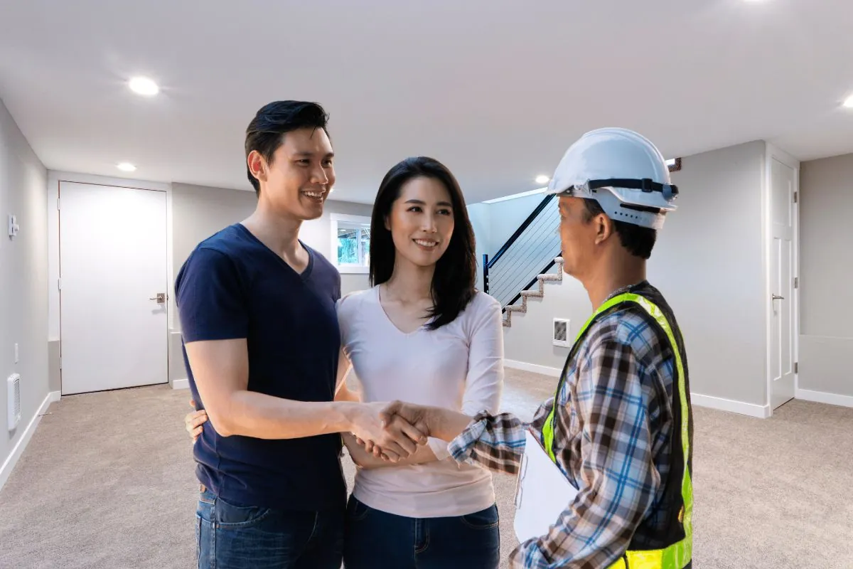 happy homeowner stand in front of contractor and shake hand